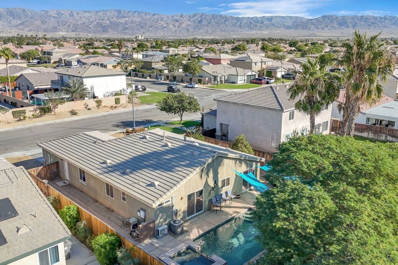 A residential area with houses, a swimming pool, and mountains in the background.