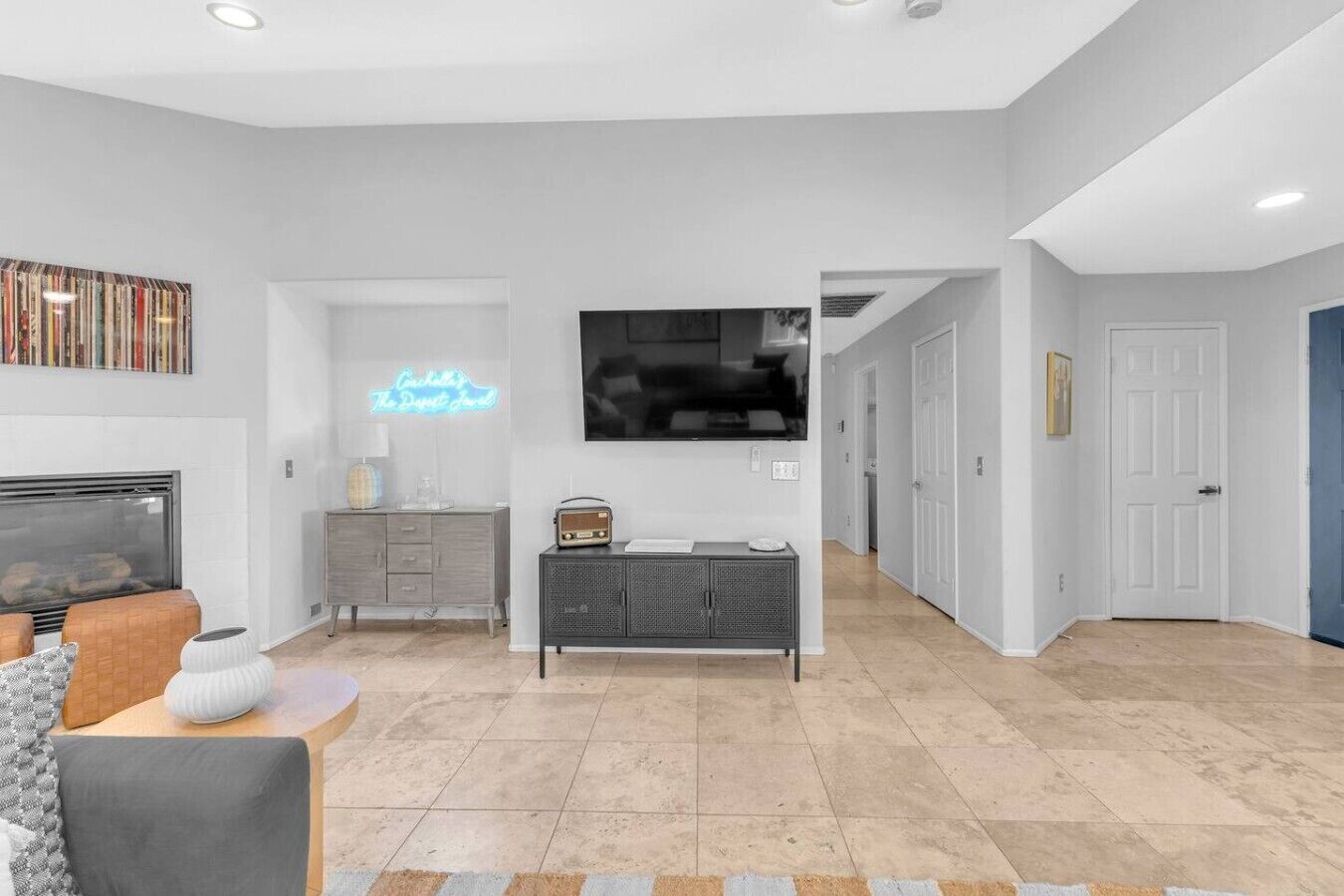 A modern living room with a fireplace, a television, and a neon sign.