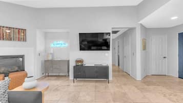 A modern living room with a fireplace, a television, and a neon sign.