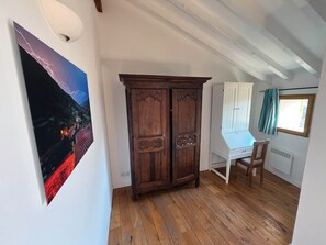 Ein Zimmer mit Holzboden, einem weißen Schrank, einem Holzschrank und einem Bild an der Wand.