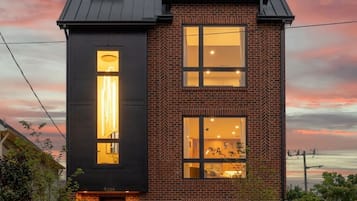 A two-story building with a brick facade and large windows, featuring a modern design with a flat roof and a visible chimney.