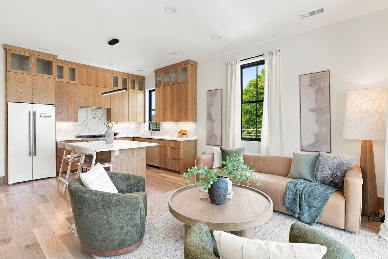 Une cuisine moderne avec des meubles en bois, un coin repas comprenant une table et des chaises, un canapé et une grande fenêtre avec des rideaux.