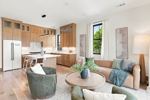 A modern kitchen with wooden cabinets, a dining area with a table and chairs, a sofa, and a large window with curtains. - 6 Bedroom Home with a City Skyline View, Hot Tub + Pool Table (Nashville)