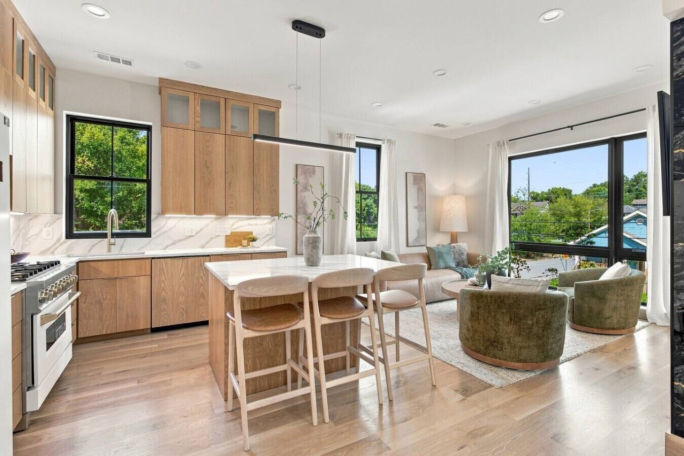 Una cocina moderna con armarios de madera, encimera de mármol y un comedor con mesa y sillas.