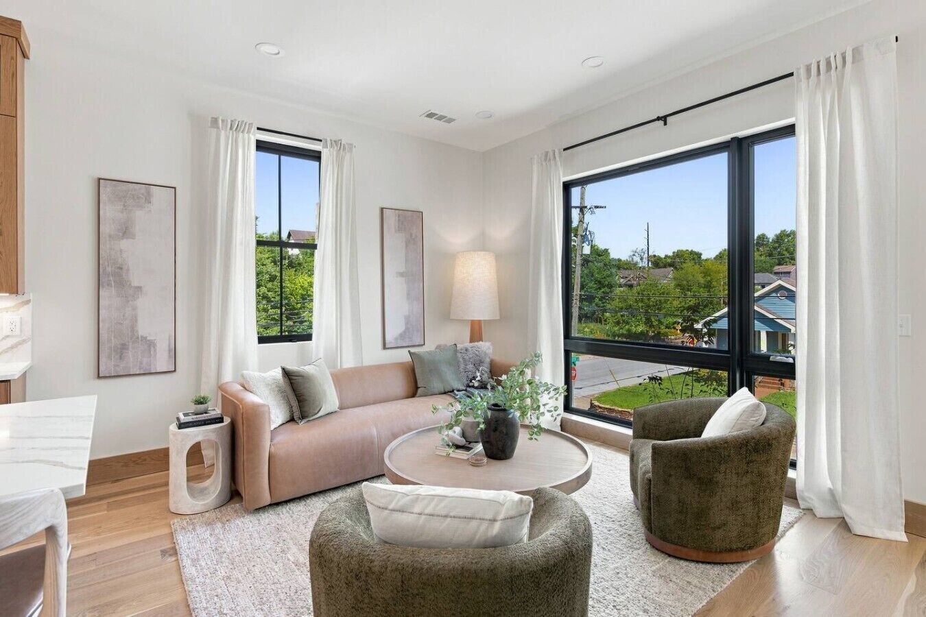 Un salon moderne comprenant un canapé, des fauteuils, une table basse et de grandes fenêtres donnant sur l’extérieur.