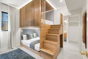 Ein modernes Schlafzimmer mit integriertem Bett, einer Holztreppe und Blick ins Freie.