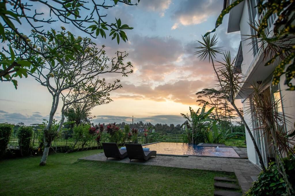 A pool area with lounge chairs, surrounded by lush greenery and a view of distant hills.
