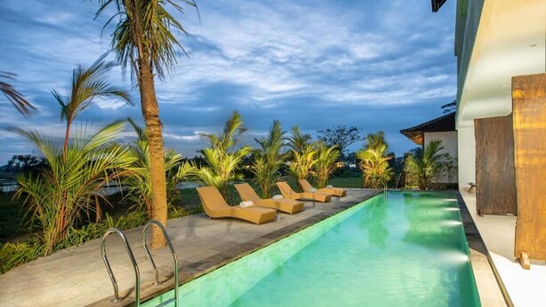 A swimming pool with lounge chairs and palm trees. - Kayun Retreat Mas Suite (Ubud)