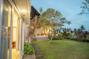 A modern house with a covered porch, a well-maintained lawn, and a variety of plants. - Kayun Retreat Mas Suite (Mas)