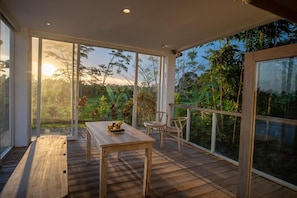 A spacious balcony with a wooden table and chairs, large windows offering a view of the surrounding greenery. - Kayun Retreat Mas Suite (Mas)