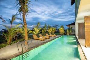 A poolside area with lounge chairs and a palm tree. - Kayun Retreat Mas Suite (Mas)