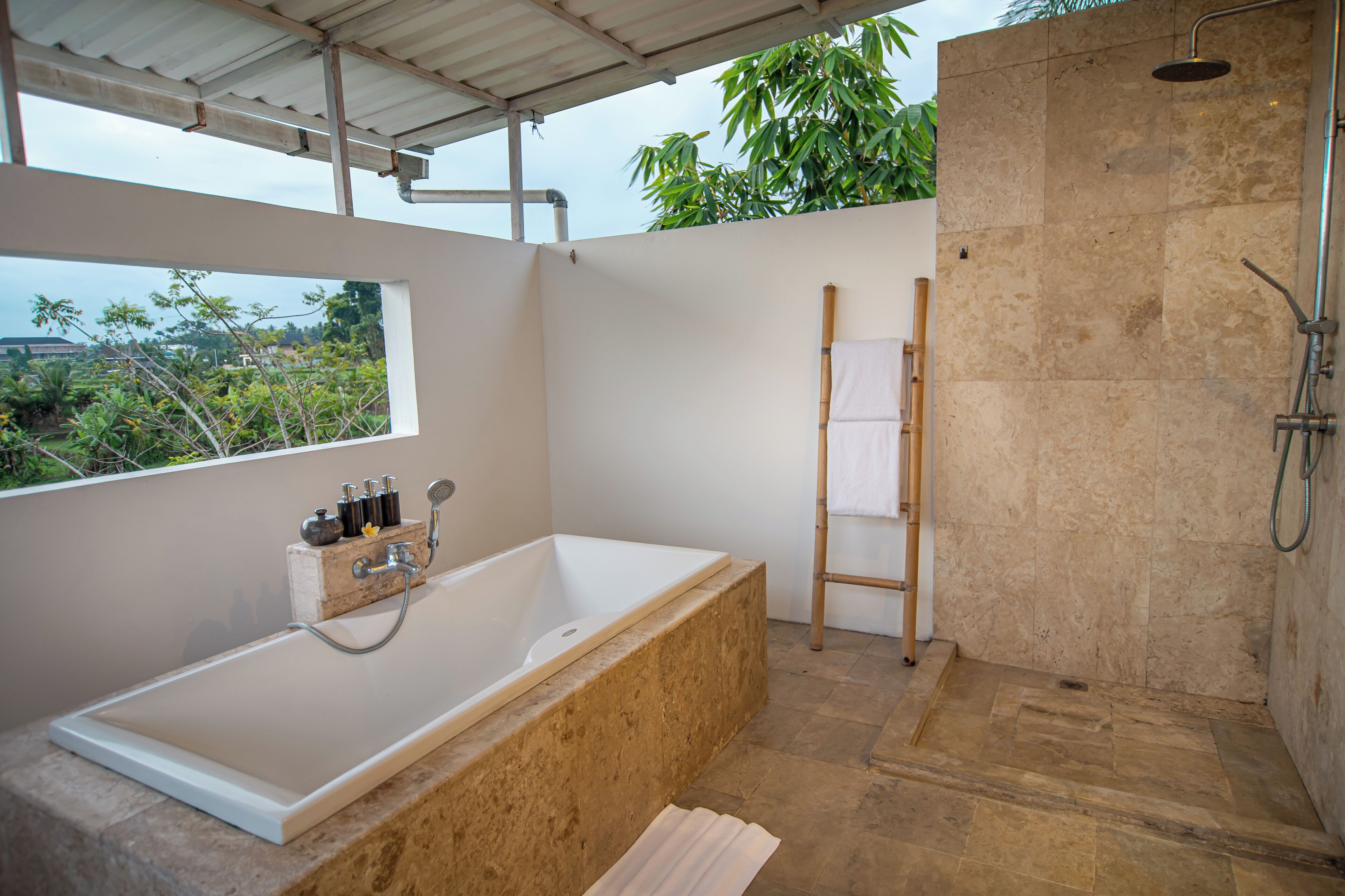 Un baño moderno con bañera, ducha y ventana con vistas a zonas verdes.
