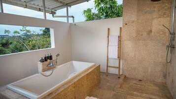 Un baño moderno con bañera, ducha y ventana con vistas a zonas verdes.