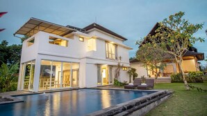 A modern two-story house with a swimming pool, large windows, and a well-maintained garden. - Kayun Retreat Mas Suite (Ubud)