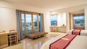 A hotel room with a balcony, a desk, two beds, and a bathroom. - Kayun Retreat Mas Suite (Ubud)