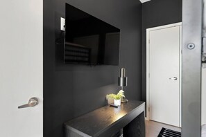 A modern bathroom with a dark wall, a mirror, a small plant on a wooden console, and a white door. - Stunning Riverview Condo - Walk to Downtown, Garage, Private Balcony (Nashville)