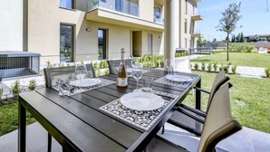 An outdoor dining area with a table set for two, a bottle of wine, and a glass. - Oasi del Garda in Desenzano - Pool, Garden, and Garage (Desenzano del Garda)