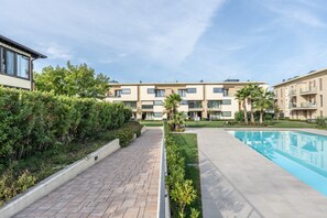 Ein modernes Wohngebäude mit Schwimmbad, gepflasterten Wegen und Grünflächen.