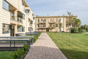 A modern apartment building with a paved walkway and small trees. - Oasi del Garda in Desenzano - Pool, Garden, and Garage (Desenzano del Garda)