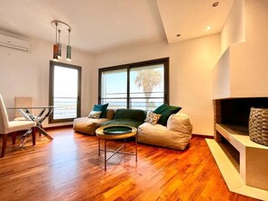 Un salon moderne avec une table basse en verre, deux canapés, une cheminée et de grandes fenêtres.