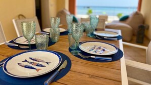 A dining table set with plates, glasses, and cutlery, overlooking a beach. - At Antico Molo Sea View: A cozy apartment near the beach. (San Cataldo)