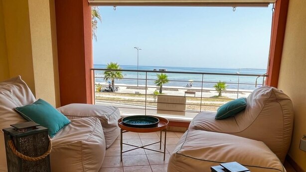 A balcony with a view of the sea, two beige sofas with teal cushions, and two decorative lanterns. - At Antico Molo Sea View: A cozy apartment near the beach. (San Cataldo)