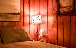 A room with a bed, a lamp with a floral pattern, a vase with dried flowers, and a painting on the wall. - Cozy 2-bedroom cabin in beautiful Shell Lake, Wisconsin. (Shell Lake)