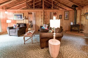 A cozy room with wooden walls and a high ceiling, furnished with two sofas, a small table, and a decorative lamp. - Cozy 2-bedroom cabin in beautiful Shell Lake, Wisconsin. (Shell Lake)
