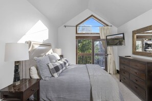 A bedroom with a bed, a dresser, a lamp, a window, and a view of the outdoors. - Mountain Village Chalet | Ski-In/Out+ Hot Tub (Mountain Village)