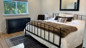 Quarto com cama, penteadeira, janela e espelho.