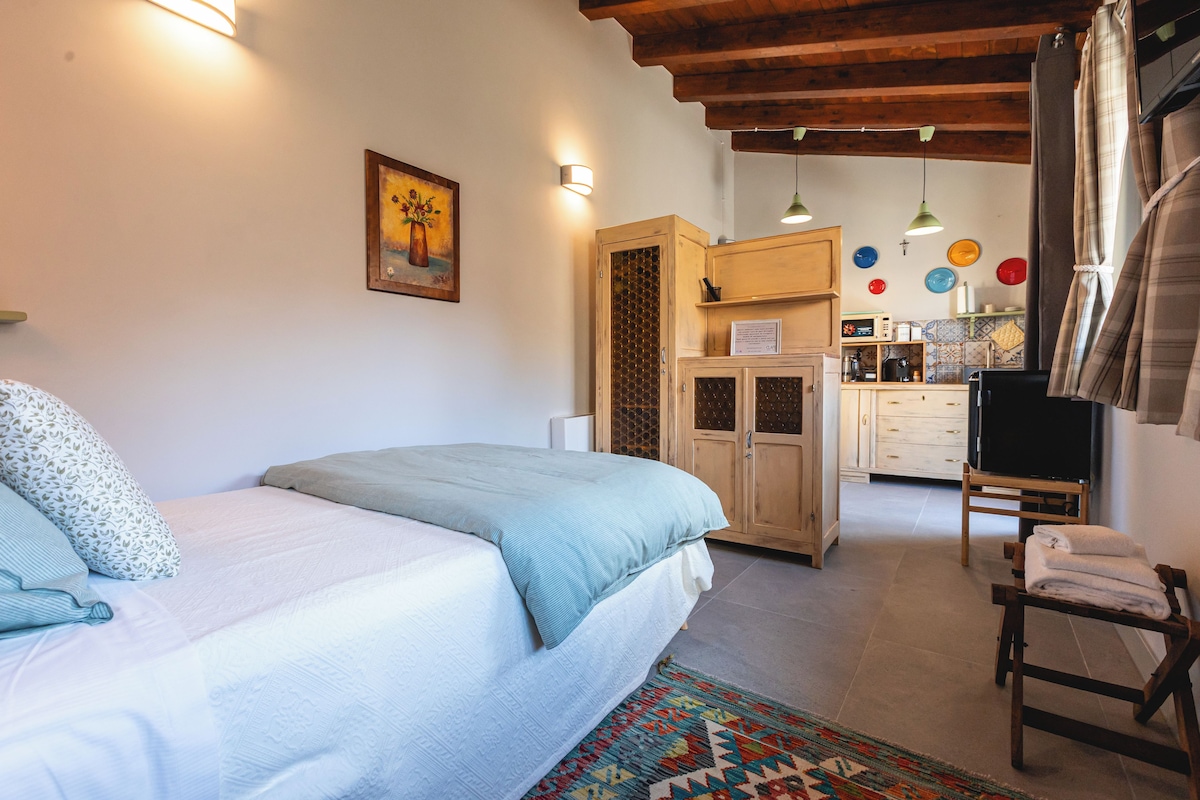 Un dormitorio con cama, una silla, una pequeña cocina y una mesa de comedor.