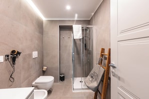 Un baño moderno con inodoro, bidé y cabina de ducha con mampara de vidrio.