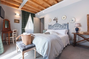 Un dormitorio con cama, mesitas de noche, una silla, un escritorio y una ventana con cortinas.