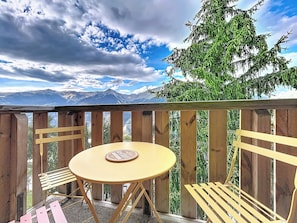 A wooden deck with a round table and two chairs, overlooking a mountainous landscape. - La Plagne Montalbert, ski-in/ski-out, in the heart of the resort, unobstructed view, ski lift. (Aime-la-Plagne)