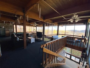 A spacious room with a wooden ceiling, a balcony with a railing, and a large window offering a view of the outdoors. - Winterplace condo lodge - Ski in Ski out (Raleigh County)