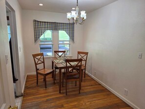A dining area with a table and four chairs, a chandelier, and a window with plaid curtains. - Ashwood Acres - 5 minutes from Winterplace!  11 Acres of room to play! (Ghent)