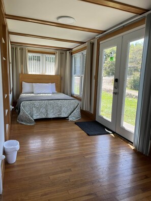 Ein Schlafzimmer mit einem hölzernen Bett, großen Fenstern und Blick ins Freie.