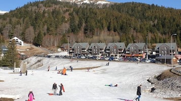 Une station de ski comprenant plusieurs bâtiments, une piste de ski et un paysage montagneux en toile de fond.