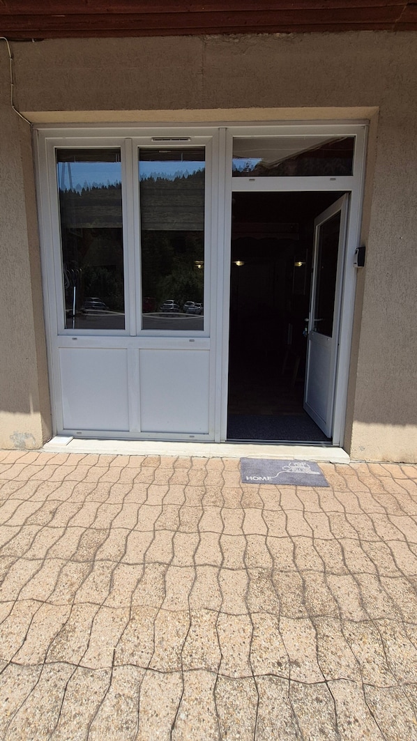A set of double doors leading into a building, with a 'HOME' mat at the entrance.
