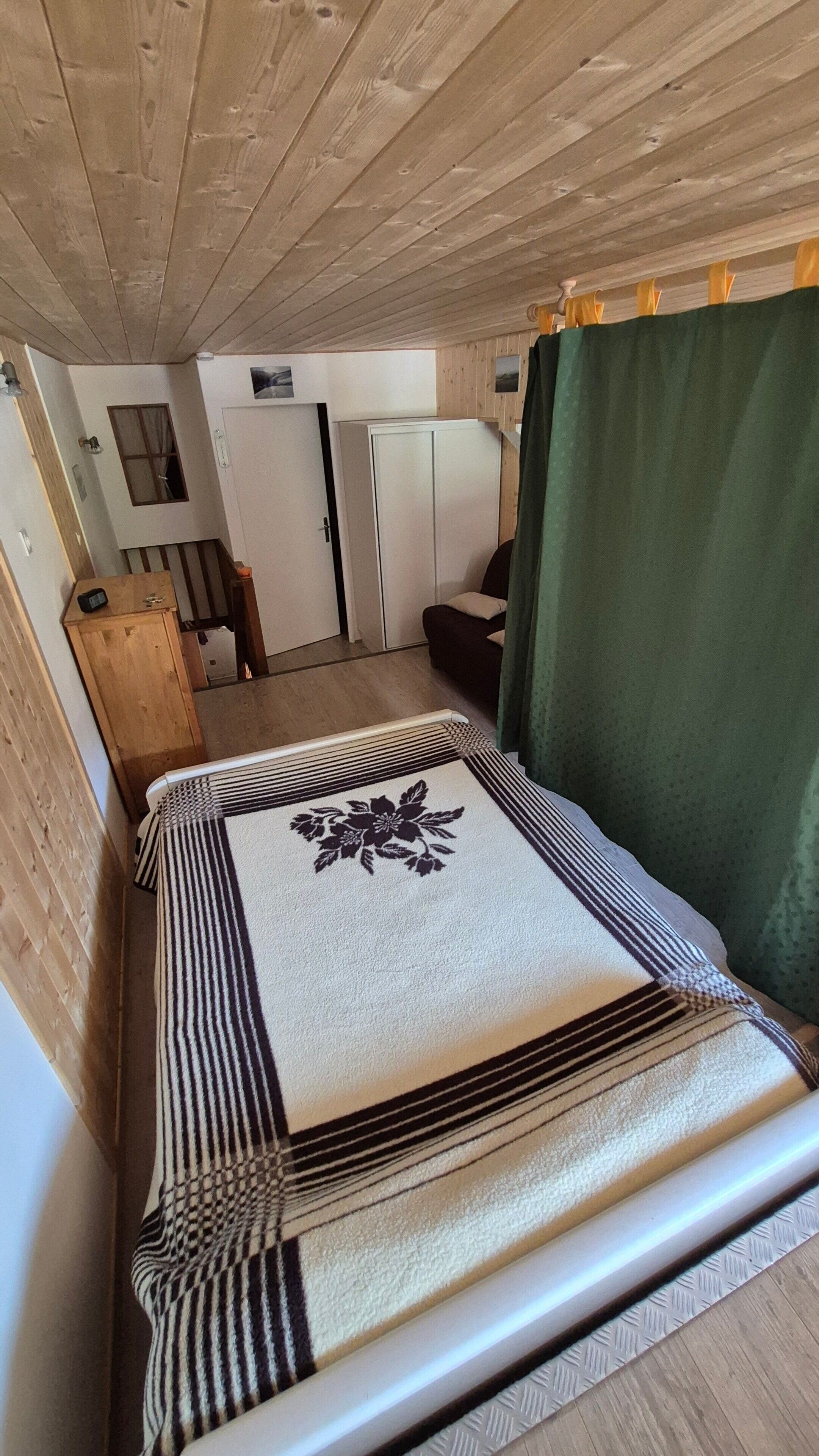 A room with a bed, a wardrobe, a small table, and a window.