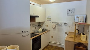 A kitchen with wooden flooring, white cabinets, a stove, and a sink. - Apartment 'Le Lioran Font D'alagnon' with Mountain View (Laveissière)