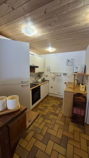 A kitchen with wooden flooring, white cabinets, a stove, and a sink. - Apartment 'Le Lioran Font D'alagnon' with Mountain View (Laveissière)