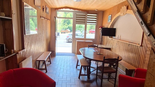 A wooden interior with a dining area, benches, and a view through a door. - Apartment 'Le Lioran Font D'alagnon' with Mountain View (Laveissière)