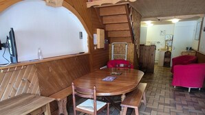 A wooden dining area with a bench and a table, a staircase, and a red sofa. - Apartment 'Le Lioran Font D'alagnon' with Mountain View (Laveissière)