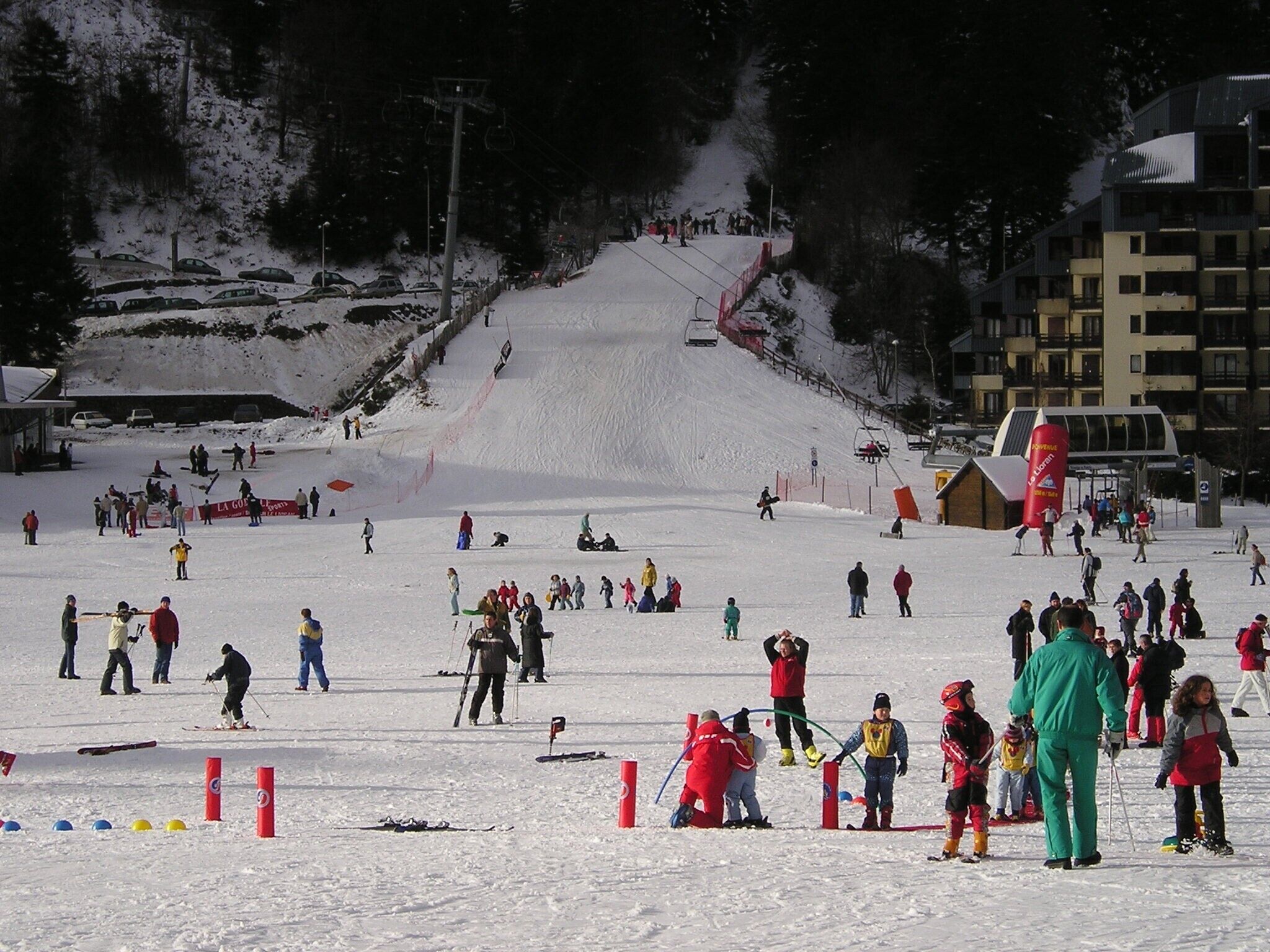 A ski resort with a ski lift, a ski slope, and a building in the background.
