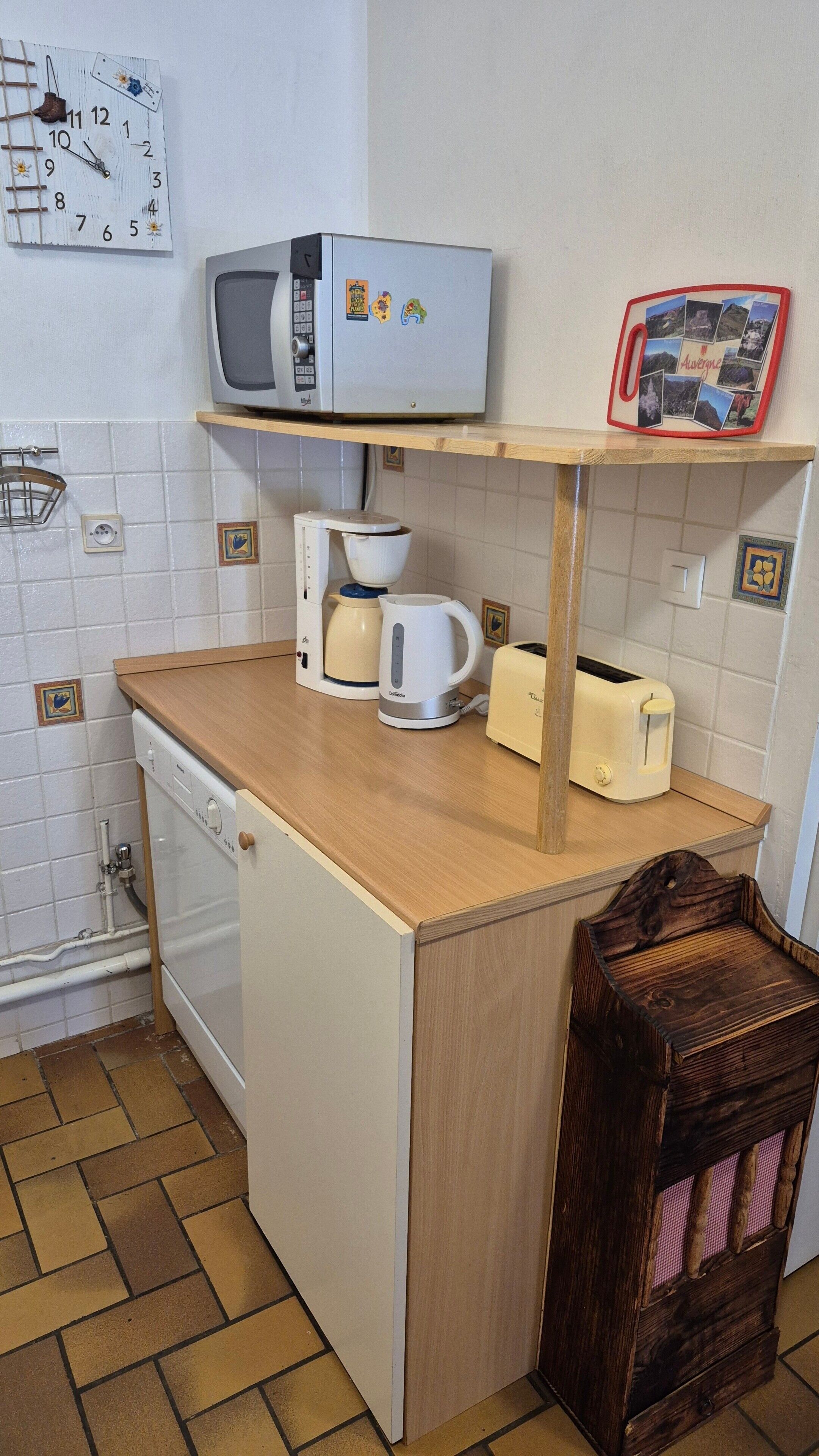 Een functionele keuken met een magnetron, broodrooster, waterkoker en een kleine koelkast.