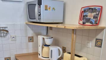 Een functionele keuken met een magnetron, broodrooster, waterkoker en een kleine koelkast.
