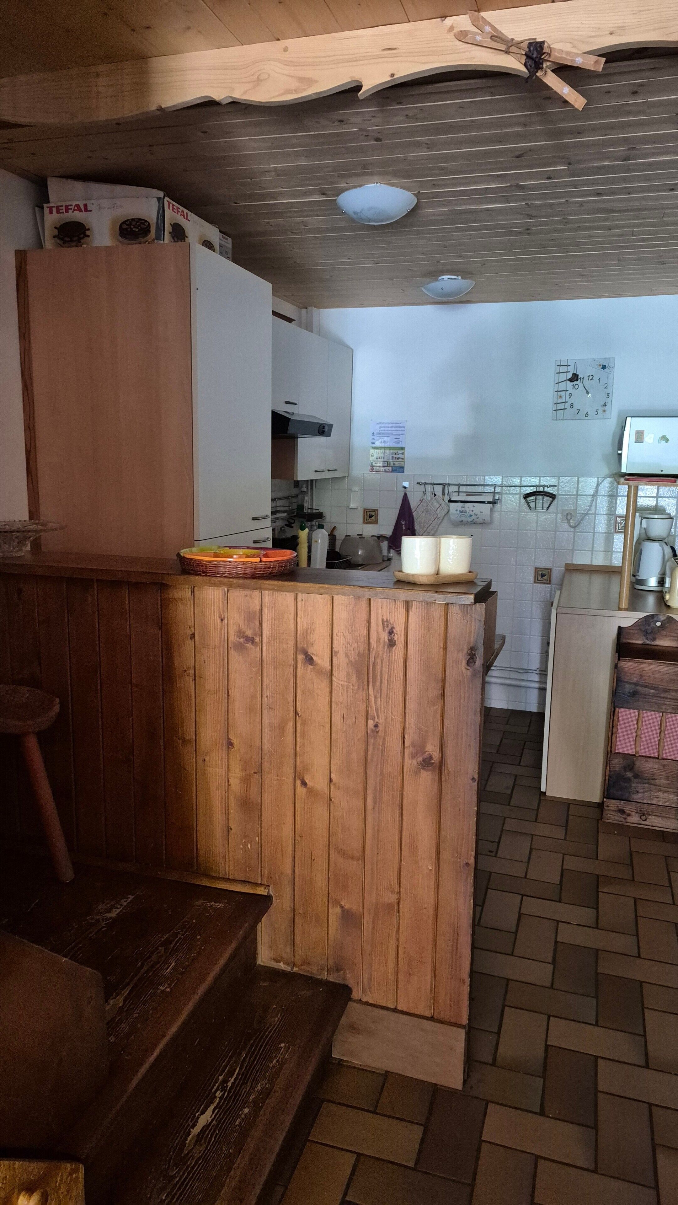 Une cuisine avec des armoires en bois, un plan de travail et un pare-feu en carreaux.