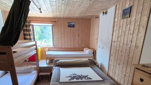 A cabin interior with bunk beds, a wooden floor, and a window with a view of trees. - Apartment 'Le Lioran Font D'alagnon' with Mountain View (Laveissière)