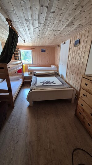 A cabin interior with bunk beds, a wooden floor, and a window with a view of trees. - Apartment 'Le Lioran Font D'alagnon' with Mountain View (Laveissière)